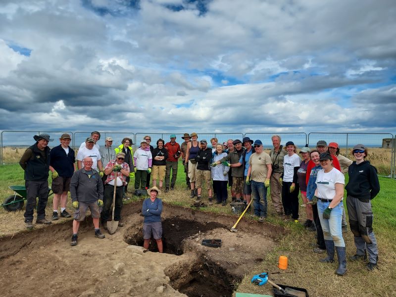 collection of people around a dug hole